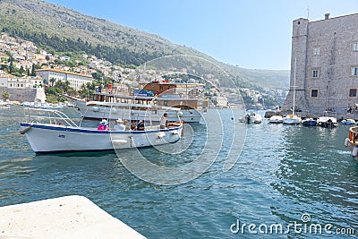 Tourists sightseeing from Old Harbour on tourist boats boat in harbour surrounded by medieval stone walls of Old Town Editorial Stock Photo