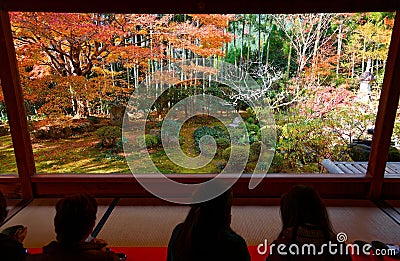 Tourists sit on the tatami floor of a tea room & enjoy the beautiful view of a Japanese courtyard garden Editorial Stock Photo
