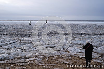 Tourists stroll along the coast of the Gulf of Finland. Sunny, fine day after a hurricane and an ice storm Editorial Stock Photo