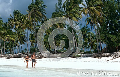 Tourists strolling on a white beach in Zanzibar Editorial Stock Photo