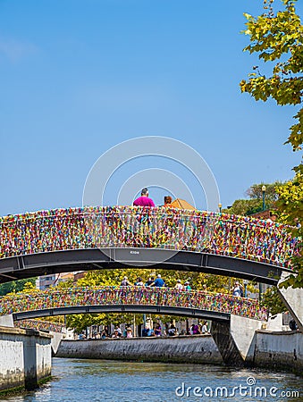 Tourists taking photos and looking at the canal from the arched bridge full of colored strips in the Portuguese Venice Editorial Stock Photo