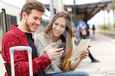 Tourists travelers consulting gps and guide in a train station Stock Photo