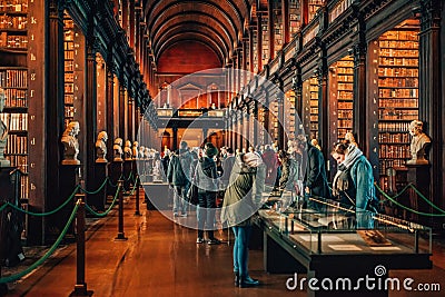 People visiting famous The Long Room in Old Library in Trinity College Dublin, Ireland. Editorial Stock Photo