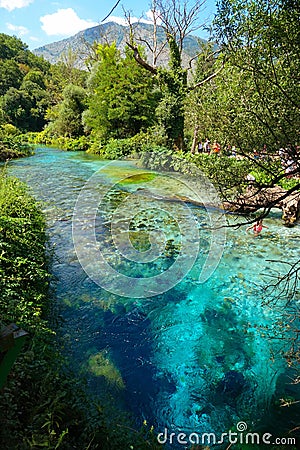 Tourists walk along the breathtaking turquoise colored river in national park. Stock Photo