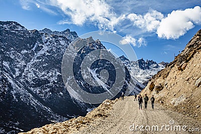 Tourists walk to black mountain with snow on the top and yellow stone ground at Thangu and Chopta valley in winter in Lachen Editorial Stock Photo