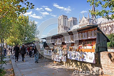 Tourists walking by the famous bookseller's boxes (bouquinistes) along the Seine River near Notre Dame in Paris Editorial Stock Photo