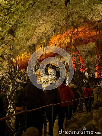Tourists walking on path among the illuminated stalactites and stalagmites Editorial Stock Photo