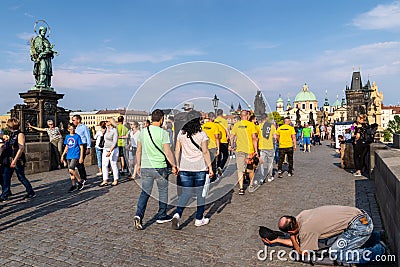 Tourists walking & posing for pictures while ignoring a begger in Charges Bridge, Prague Editorial Stock Photo