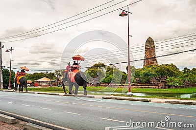 Tourists wear a mask to sit on the back of an elephant to visit Rama Temple in the Ayutthaya Historical Park area. Editorial Stock Photo