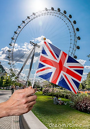 Toursist is holding flag of Great Britain in hand. London Eye in background. Editorial Stock Photo