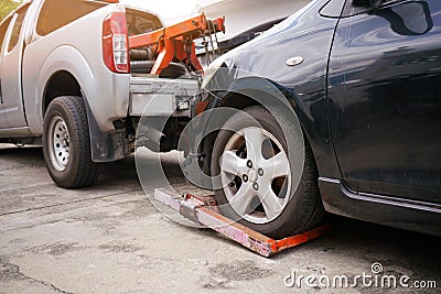 Tow truck picking up and towing old broken down car on a roadside Stock Photo