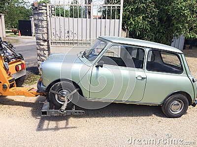 Tow truck towing a small car view from side roadside assistance lorry with vintage mini car Stock Photo