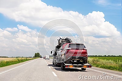 Tow truck trailer on highway carrying three damaged cars sold on insurance car auctions for repair and recovery. Vehicles Stock Photo