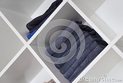 Towels in wardrobe. Neat organized wardrobe. Order in clothing storage. Minimalism in household. Modern commode. Spa interior. Stock Photo