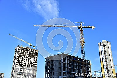 Tower cranes in action during construction residential building on blue sky background. Builder workers during formwork and Stock Photo