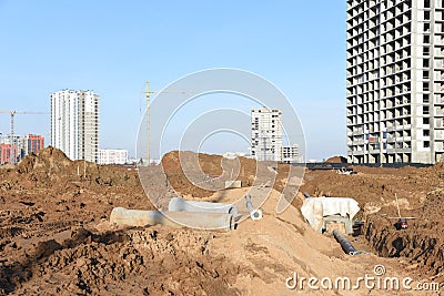 Tower cranes constructing a new residential build. Laying or replacement of underground storm sewer pipes. Concrete drainage pipe Stock Photo