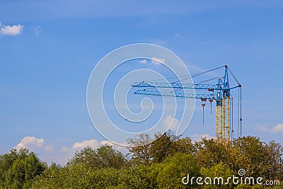 Tower cranes on a construction site near building and green tree Stock Photo
