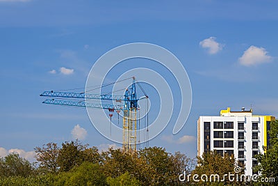 Tower cranes on a construction site near building and green tree Stock Photo