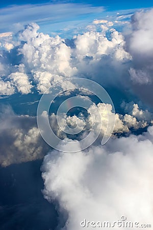 Towering cloudscape from airplane view with a little rainbow right in the middle Stock Photo