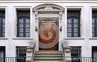 townhouse entrance with ornate stone design and elegant carved wooden front door Stock Photo