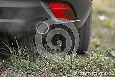 Toxic CO2 exhaust fumes from the exhaust pipe of a car parked on the lawn. Stock Photo