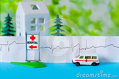 Toy ambulance car cardiogram house tree blue green hospital sign background Editorial Stock Photo
