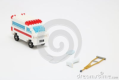 Toy ambulance car, miniature drop, gibbs, and crutch on white background. Stock Photo