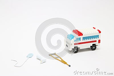 Toy ambulance car, miniature drop, gibbs, and crutch on white background. Stock Photo