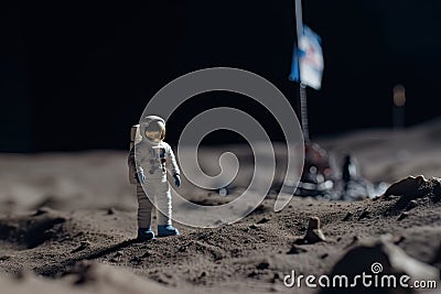 The toy of the astronaut stands on the moon's surface Stock Photo