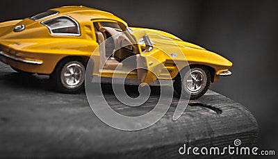 Toy car model Corvette Sting Ray 1963 year. Yellow color. Side view. Opened door. Close-up. Macro. Editorial Stock Photo