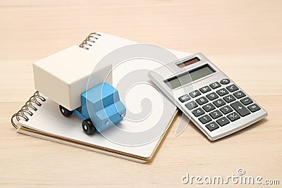 Toy car trucks, a notebook, and a calculator on wood. Stock Photo