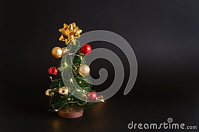 Toy christmas tree with balls on a black background with a garland. Cute Stock Photo