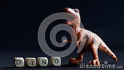 Toy dinosaur similar to Velociraptor, Tyrannosaurus, Allosaurus, Megalosaurus, or Plateosaurus stands on a black background next Stock Photo