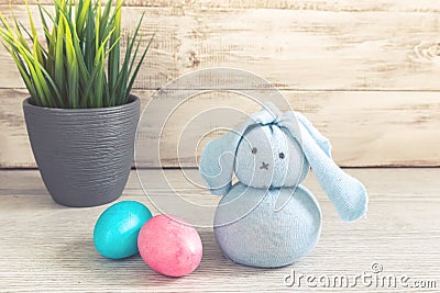 Toy Easter bunny and painted eggs on a wooden background Stock Photo