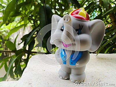 A Toy Elephant wearing a blue coat and a hat with long trunk and a smiling face. Stock Photo