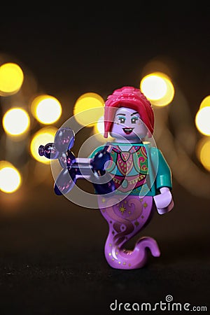 Toy female genie figure with red hair and lips holding a purple balloon animal Editorial Stock Photo