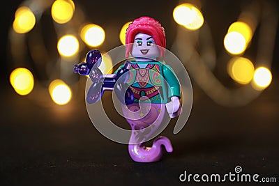 Toy female genie figure with red hair and lips holding a purple balloon animal Editorial Stock Photo