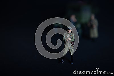 A figure of a man in a military German uniform. In the background of a vague truck and two soldiers Stock Photo