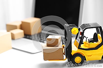 Toy forklift with boxes near laptop. Logistics and wholesale concept Stock Photo