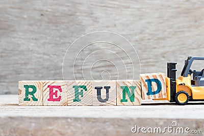 Toy forklift hold block D to complete word refund on wood background Stock Photo