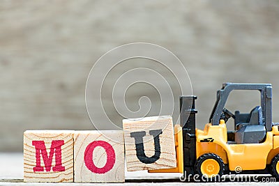 Toy forklift hold letter block u in word mou abbreviation of memorandum of understanding Stock Photo