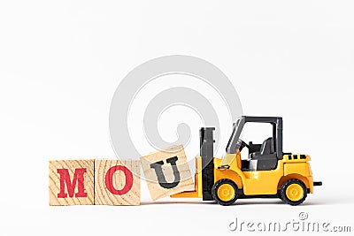 Toy forklift hold wood block U to complete word MOU Abbreviation of memorandum of understanding on white background Stock Photo