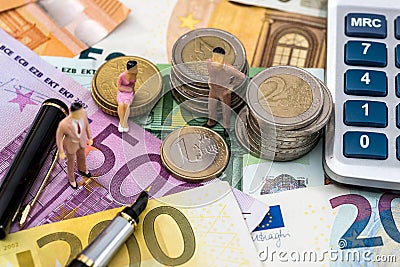 Toy people sit on euro coin with calculator, pen and euro bills Stock Photo