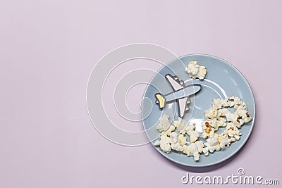 A toy plane flies on a blue plate above popcorn clouds Stock Photo