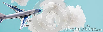 Toy plane flying among white fluffy clouds made of cotton wool isolated on blue, panoramic shot Stock Photo