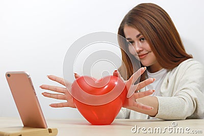 Toy red heart. Girl holds her heart in front of phone screen. Talking on Internet. Valentines Day, communication by videoconferen Stock Photo