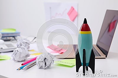 Toy rocket, laptop and crumpled paper on messy table indoors, space for text. Startup concept Stock Photo