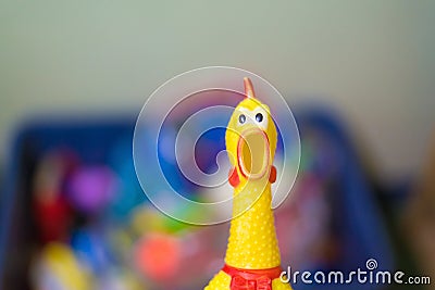 Toy rubber shriek yellow chicken on blur toy background in messy Stock Photo