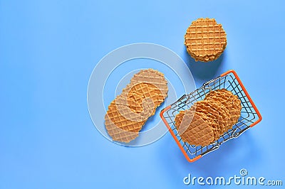 Toy shopping cart with many thin round waffles on purple background. Purchase or selling concept. Top view Stock Photo