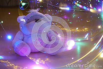 A toy teddy bear surrounded by colored lights. Abstract fairytale magic background Stock Photo